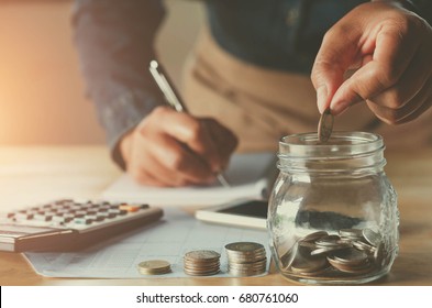 business accounting with saving money with hand putting coins in jug glass concept financial