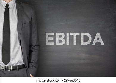 Business acronym EBITDA Earnings before interest and taxes depreciation and amortization on black blackboard with businessman
