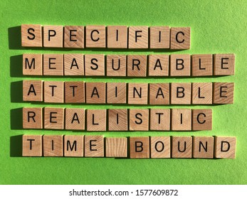 Business acronym, SMART, Specific, Measurable, Attainable, Realistic, Time Bound, in 3d wooden alphabet letters on a green background. Flat lay, from above - Shutterstock ID 1577609872