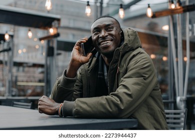 Business african american man wear on suit and sitting at office and speaking on phone. Man talking on cell phone in restaurant. Portrait of smiling man talking on cell phone while sitting. - Shutterstock ID 2273944437