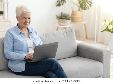 Business After Retirement. Smiling Senior Woman Working On Laptop Computer At Home, Sitting On Couch In Cozy Living Room, Free Space - Powered by Shutterstock