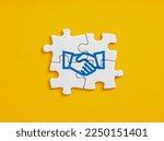 Business agreement or consensus building of different parties. Strategic alliance, teamwork or business partnership concept. Jigsaw puzzle pieces with handshake icon.