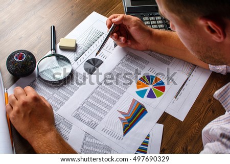 Business analysis - calculator, sheet, graphs (business report) and analyst hand, top view