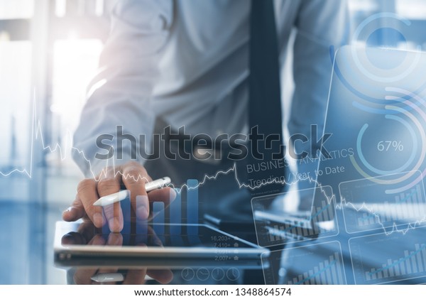 Business analysis, modern technology concept.\
Businessman, analyzing business data on digital tablet and laptop\
computer in office with augmented reality analytics computer\
dashboard on virtual\
screen