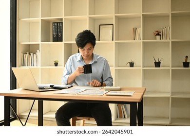 A Business Analyst Man Using Calculator and Charts for Data Analysis.