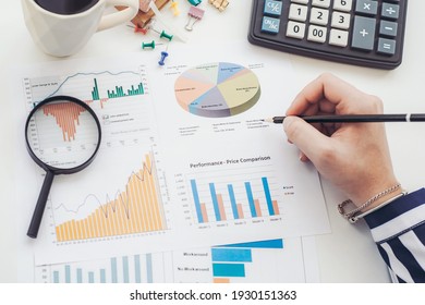 Business analyst working - hand with pen, calculator, coffee, magnifier, worksheet and graph - Powered by Shutterstock