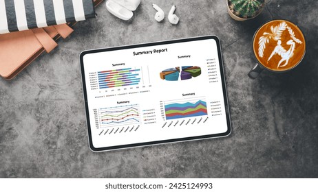Business analytics concept, A digital tablet on a marble surface showing graphs and pie charts in a business summary report, alongside a coffee and earbuds.