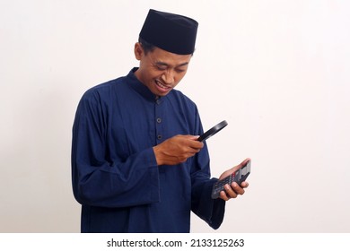 Business Analytics And Statistics. Asian Man Using A Magnifying Glass On Calculator