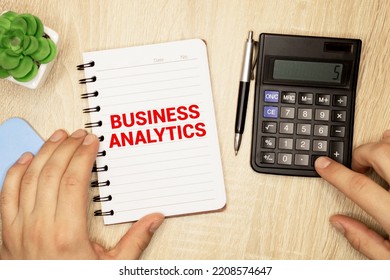 Business Analytics, Text Concept. Office Workplace Table With Calculator, Graphs, Reports And The Text Business Analytics On A Small Piece Of Paper On Multicolored Background.