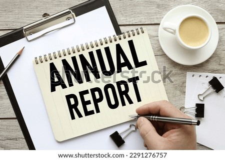 Business Annual Report text on a black folder near a cup of coffee. light wooden background