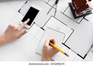 business, architecture, building, construction and people concept - close up of architect hand with living house blueprint and smarphone writing to notebook - Shutterstock ID 414200674