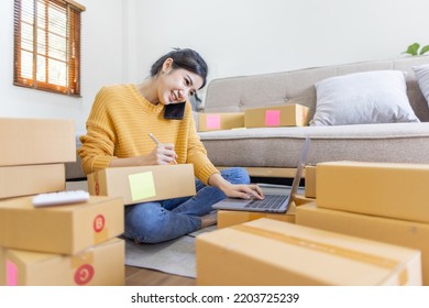 Business Asian Women Sit On Sofa Use Laptop Computer Checking Customer Order Online Shipping Box At Home. Starting Small Business Entrepreneur SME Freelance. Online Business, Work At Home SME Concept.