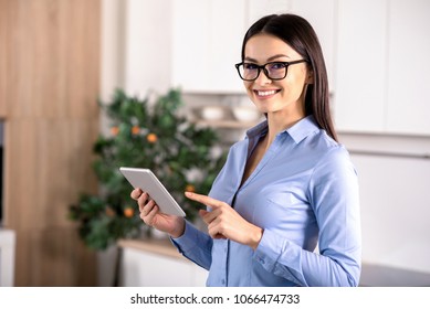 Business attitude. Positive nice woman using her tablet while standing in the kitchen - Shutterstock ID 1066474733
