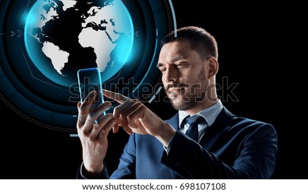 business, augmented reality and modern technology concept - businessman working with transparent smartphone and virtual earth globe hologram over black background