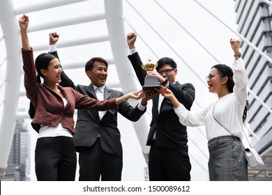 business background of asian business people being cheerful for being winner in business competition contest with hand holding trophy and award cerfiticate