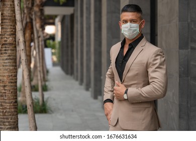 Business Background Of Caucasian Businessman Wearing Medical Mask For Coronavirus Covid 19 Protection Standing Beside Office Building In City, Working In Coronavirus Covid 19 Pandemic Situation