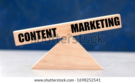 Business balance between CONTENT and MARKETING on wooden scales on a dark background