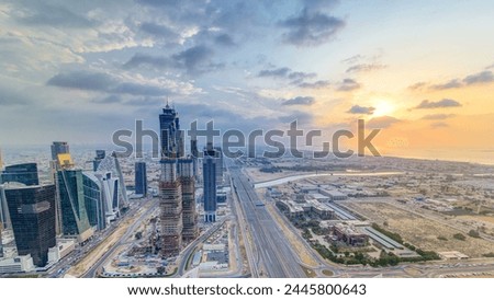 Business bay towers with sunset aerial. Rooftop view of some skyscrapers and new towers under construction. Dubai water canal with bridges and Sheikh Zayed road traffic. Cloudy colorful evening sky