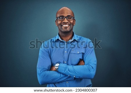 Business, black man and portrait with arms crossed in a studio feeling proud from auditor work. Blue background, smile and African employee with success and leadership vision with glasses and idea