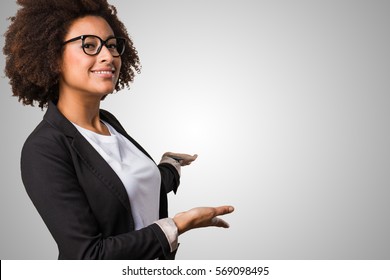 Business Black Woman Doing Welcome Gesture On A Grey Background