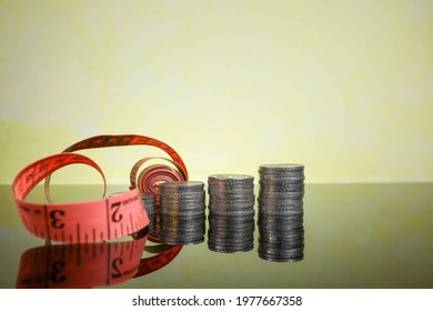 Business And Budget Cut Concept.  Stacked Coins Reflected On The Glass Table With Measuring Tape At The Side