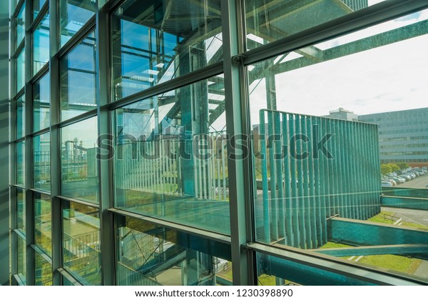 business\
building balcony with vertical and horizontal steel silver pylons\
against buildings and blue sky with white clouds, office balcony in\
sunshine. window frame with transparent\
glass