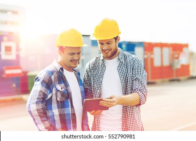 Business, Building, Construction, Technology And People Concept - Two Smiling Builders In Hardhats Looking At Tablet Pc Computer Outdoors