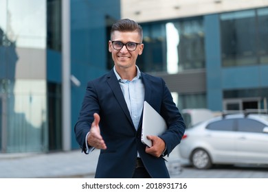 Business. Businessman Giving Hand For Handshake Welcome Gesture Adult Caucasian Male Business Person Holding Closed Laptop Give Hand Ready Handshake Office Building Background