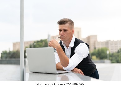 Business. Businessman Using Laptop Outdoors. Serious Pensive Caucasian Male Eyeglasses Business Person Computer Outside Modern Technology Concept Young Adult Manager Crisis Thinking Trouble Idea 