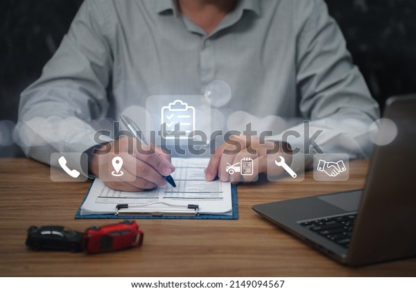 Business and car\
insurance concept, Man use pen checklist details of the accident\
use laptop and car accident model on the table with virtual screen\
in the background