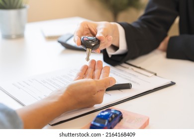 Business car rental company service, Close up hand of agent dealer giving, holding car key to customer renter, new owner after signed rental, purchase contract in document, vehicle sales agreement.