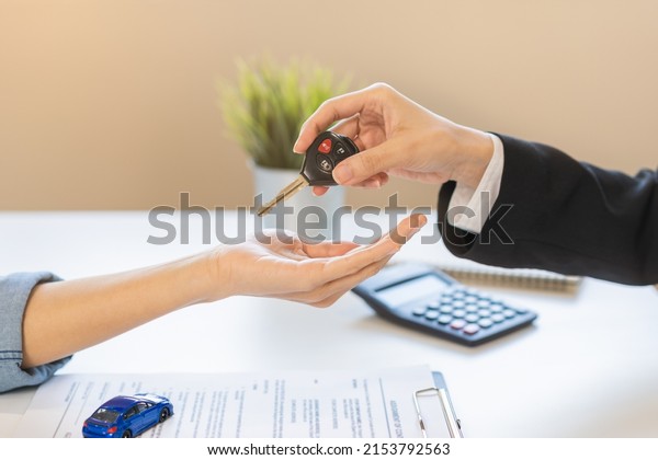 Business car rental company service, Close up\
hand of agent dealer giving, holding car key to customer renter,\
new owner after signed rental, purchase contract in document,\
vehicle sales\
agreement.