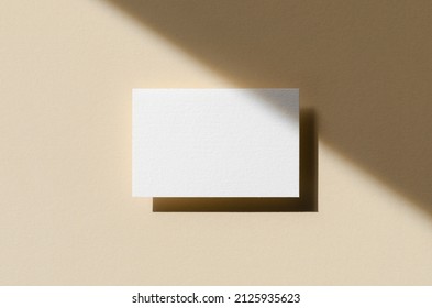 Business card mockup on a beige background with shadow overlay. 85x55 mm.