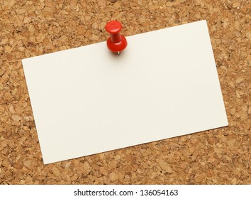 Business Card Posted On A Cork Board With Red Tack Pin.