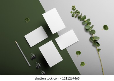 Business cards blank mockup and stationery set, with floral elements, top view, on white and green background.