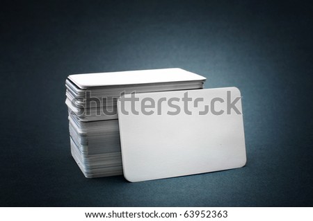 Business cards with rounded corners. The pile of blank business cards lays propped up another business card.