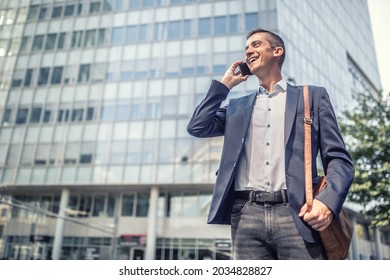 Business Casual Dress For Man Who Talks On A Cell Phone In Front Of The Office Building Smiling.