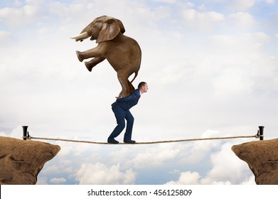 Business Challenge Concept Businessman Carrying An Elephant Across A Tightrope Chasm