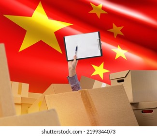 Business With China. Chaos Boxes And PRC Flag. Hand With Clipboard. Cardboard Parcels From China Concept. Managers Hand With White Sheet Of Paper. Business Partnership With Peoples Republic Of China