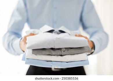business, clothing and people concept - close up of businessman holding folded shirts