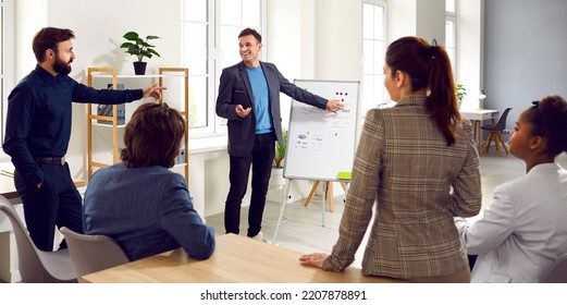 Business Coach Meets With Team Of People. Happy Positive Man Standing By Office Whiteboard, Talking About Corporate Career Development, Sharing Expertise, Making Suggestions For Project Improvement