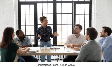 Business coaching. Friendly indian female coach delivering training to diverse group of young employees, capable millennial mixed race woman tutor explaining sales strategy to multiethnic intern team