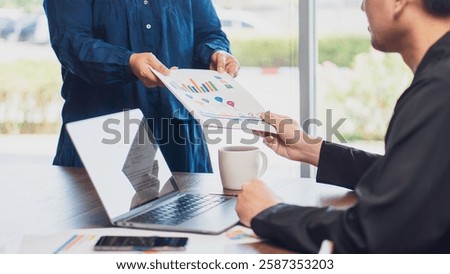 business collaboration, teamwork, and data analysis, featuring handing over a financial report with charts and graphs to a colleague in an office. business strategy, financial planning professional