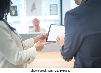 Business Colleague Showing Something On Digital Tablet To Another Coworker. Office Setting.