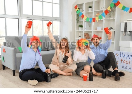 Business colleagues with champagne celebrating April Fools' Day at office party