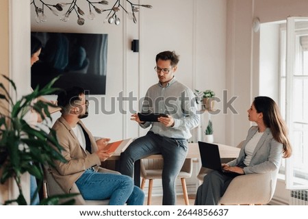 Business colleagues collaborating and using digital tablet and laptop during a productive meeting in a modern office space