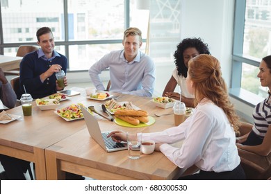 Business colleagues discussing while sitting around breakfast table at office cafeteria