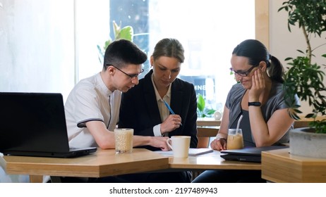 Business Colleagues Having Meeting In A Cafe, Viewing Data In Papers