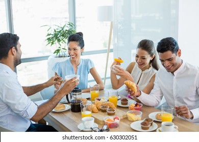 Business colleagues interacting with each other while having breakfast in office cafeteria - Powered by Shutterstock