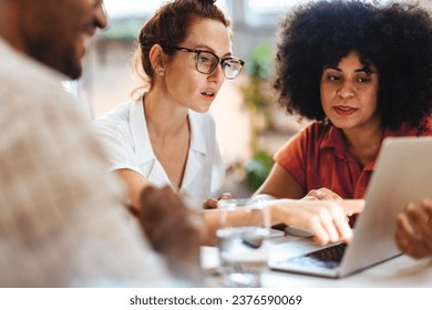 Business colleagues meeting over a project in a café, exchanging ideas and discussing the way forward for their team. Group of business professionals planning a collaboration. - Powered by Shutterstock